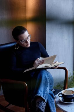 Genç bir kız bir kafede oturmuş kitap okuyor. Eğitim ve uzak çalışma kavramı 