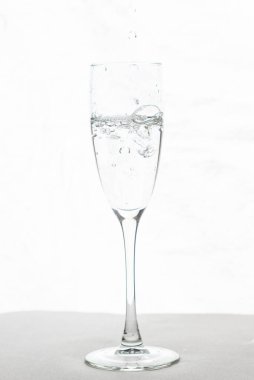 Beyaz arka planda izole edilmiş şampanya bardağı suyunu dolduruyorum.