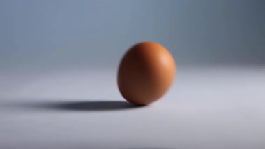 Paskalya yumurtası. Mavi masanın üzerinde yuvarlanan video yumurtalarını kapat. Tatil dekorasyonu. Bir kadın yumurtayla yuvarlanıyor. Bir kadının elinde tavuk yumurtası.