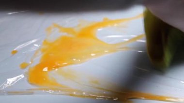  Bir tavuk yumurtası masaya düşmekten kırılır. Yüksek kalitede FullHD görüntüsü. Mavi arka planda tavuk yumurtası.