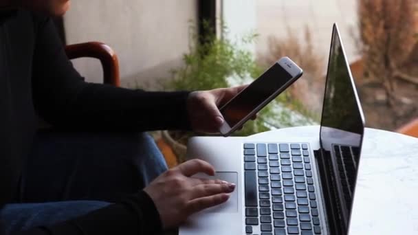 Una mujer se sienta en un café y trabaja en un portátil. — Vídeos de Stock