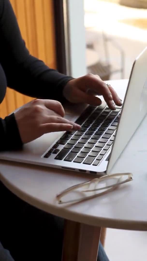 En kvinna sitter på ett kafé och jobbar på en laptop. — Stockvideo
