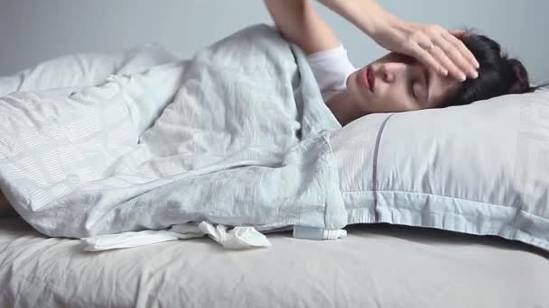 一个年轻的女人在床上感觉很冷 她正试图在毯子下取暖 发烧的概念 寒冷天气的概念 躺在床上发烧的女人 — 图库视频影像