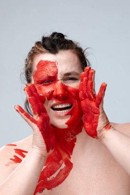 Yüzü boyalı bir kadın portresi. Yaratıcı makyaj ve parlak stil. Yüzü renkli bir kız. Sanat güzelliği. Yüzünde renkli boya olan bir kız.. 