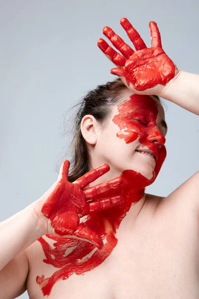 Yüzü boyalı bir kadın portresi. Yaratıcı makyaj ve parlak stil. Yüzü renkli bir kız. Sanat güzelliği. Yüzünde renkli boya olan bir kız.. 