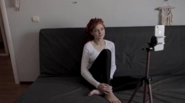 Evinde akıllı telefon ve tripodu kullanarak video kaydeden veya canlı yayın yapan bir kadın blogcu. Canlı yayın yapan canlı yayın sunucusu, dijital sosyal medya kaydediyor.