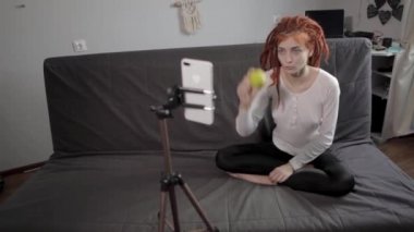 Evinde akıllı telefon ve tripodu kullanarak video kaydeden veya canlı yayın yapan bir kadın blogcu. Canlı yayın yapan canlı yayın sunucusu, dijital sosyal medya kaydediyor.