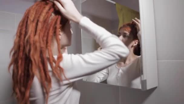 Uma Jovem Com Dreadlocks Vermelhos Olha Espelho Laços Dreadlocks Banheiro — Vídeo de Stock