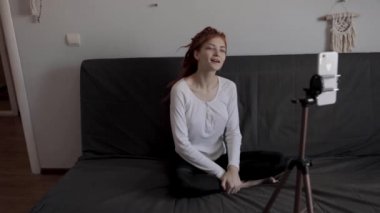 Evinde akıllı telefon ve tripodu kullanarak video kaydeden veya canlı yayın yapan bir kadın blogcu. Canlı yayın yapan canlı yayın sunucusu, dijital sosyal medya kaydediyor.