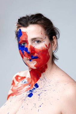 Yüzü boyalı bir kadın portresi. Yaratıcı makyaj ve parlak stil. Yüzü renkli bir kız. Sanat güzelliği. Yüzünde renkli boya olan bir kız.. 