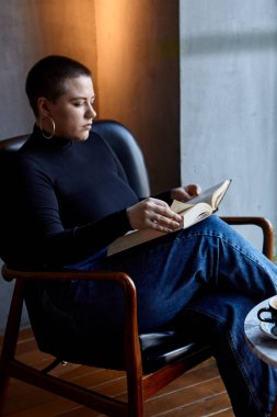 Genç bir kız bir kafede oturmuş kitap okuyor. Eğitim ve uzak çalışma kavramı 