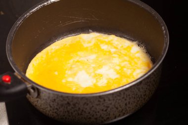 Mutfakta salata pişiriyorum. Tezgahın üzerinde bir kesme tahtası ve bir bıçak var. Sebzeler ve bitkiler yakınlarda serili.