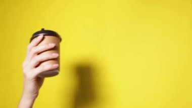 Siyah kapaklı iki bardak kahverengi kağıt tutan eller. İki özel kahve ya da tanıtım. Sarı ekranda iki bardak tutan eller. Çay ya da kahve. Siyah kapaklı kahverengi kağıt bardak..