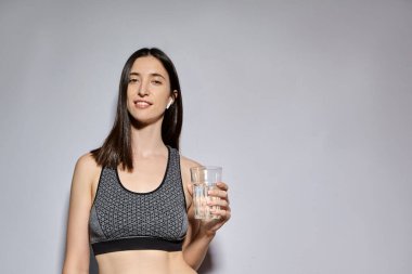 Spor elbiseli ve kablosuz kulaklıklı bir kadın su içiyor. Sağlıklı yaşam tarzı ve spor aktiviteleri kavramı