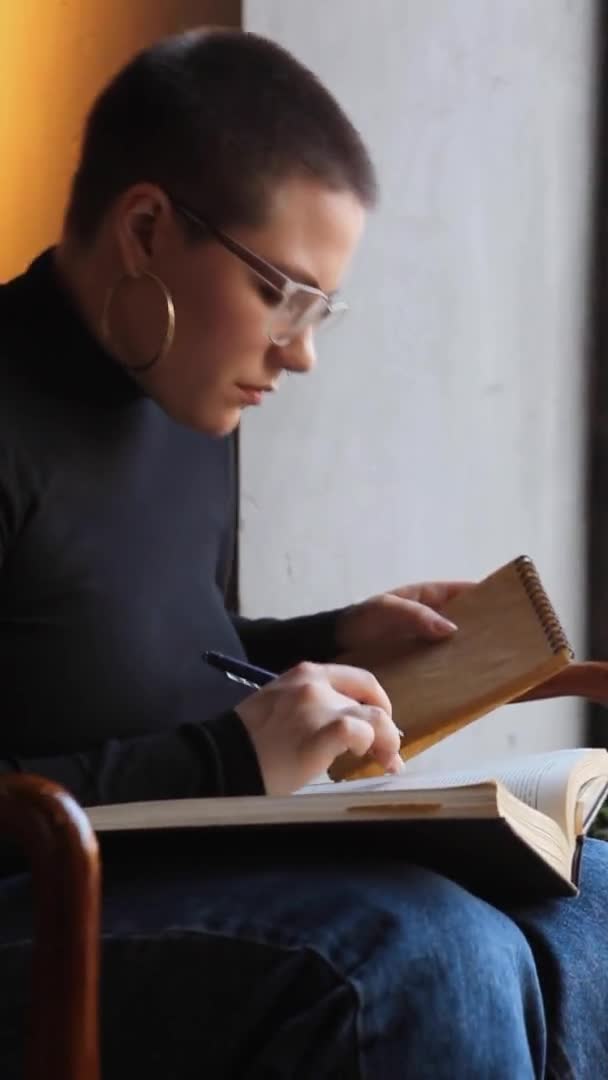 Egy Szemüveges Rövid Hajú Fiatal Lány Egy Kávézóban Könyvet Olvas — Stock videók
