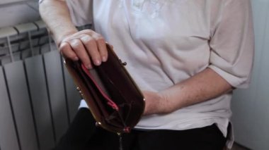 Yaşlı kadın parayı sayıyor. Yaşlı, beyaz, yaşlı, beyaz saçlı bir kadın çantasından para alıp sayıyor. Eski eller ve boş bir cüzdan.. 