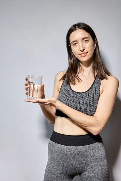 Kobieta Sportowej Odzieży Słuchawkami Bezprzewodowymi Pije Wodę Koncepcja Zdrowego Trybu — Zdjęcie stockowe