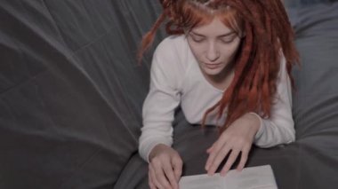 Genç ve güzel bir kadın evdeki kanepede uzanıyor ve kitap okuyor. Bir kadın telefona cevap vermek için okumayı yarıda kesiyor. Rastalı kızıl saçlı bir kız evde dinleniyor.