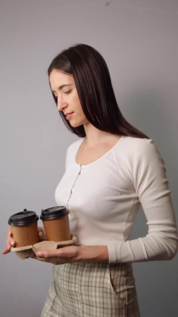 Женщина держит две чашки коричневой бумаги с черной крышкой — стоковое видео