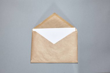 Gri arka planda kahverengi bir zarf. El işi zarfı, gri masanın üzerinde bir dal. Davetiye kartı modeli. Düz konum, üst görünüm, kopyalama alanı, alaycı