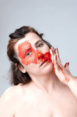 Yüzü boyalı bir kadın portresi. Yaratıcı makyaj ve parlak stil. Yüzü renkli bir kız. Sanat güzelliği. Yüzünde renkli boya olan bir kız.. 