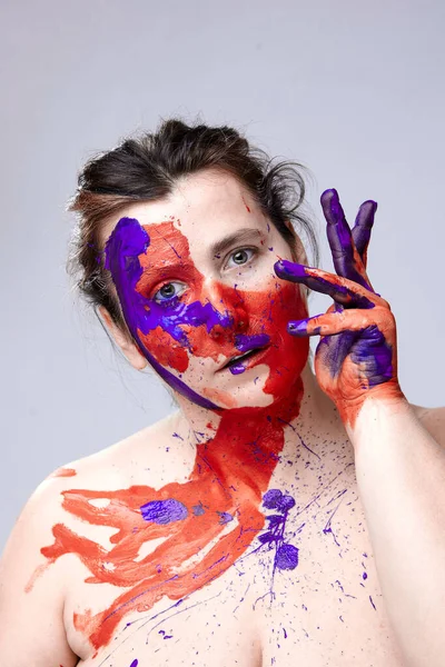 Portrait of a woman with a painted face. Creative makeup and bright style.Girl with colored face painted. Art beauty image.girl with colorful paint on her face.