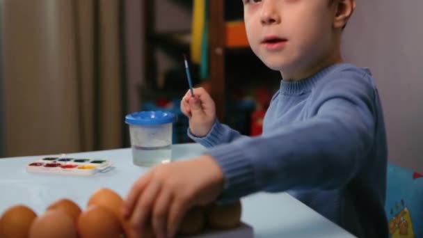 Een Klein Kind Schildert Een Paaseieren Aan Tafel Een Blauwe — Stockvideo
