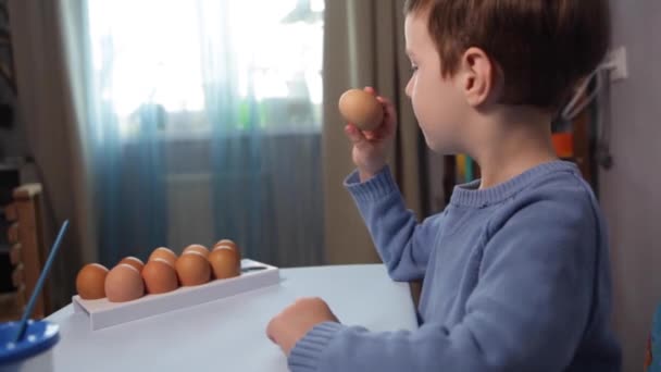 Een Klein Kind Schildert Een Paaseieren Aan Tafel Een Blauwe — Stockvideo