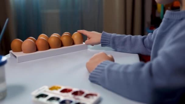 Een Klein Kind Schildert Een Paaseieren Aan Tafel Een Blauwe — Stockvideo