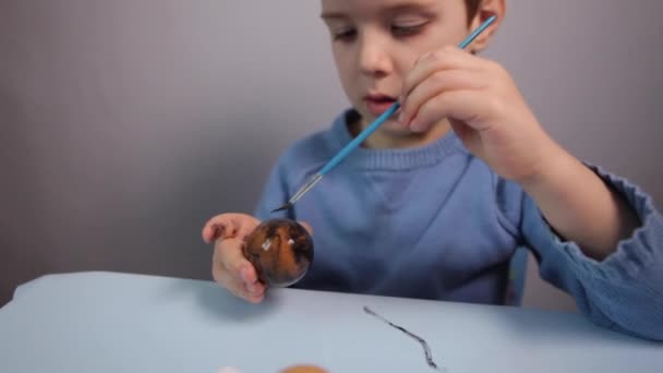 Küçük Bir Çocuk Masaya Mavi Bir Arka Plan Üzerine Paskalya — Stok video