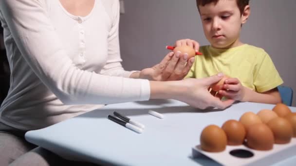 Bir Çocuk Anne Masaya Mavi Bir Arkaplan Üzerine Paskalya Yumurtası — Stok video