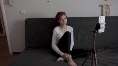 Evinde akıllı telefon ve tripodu kullanarak video kaydeden veya canlı yayın yapan bir kadın blogcu. Canlı yayın yapan canlı yayın sunucusu, dijital sosyal medya kaydediyor.