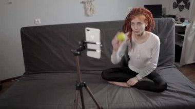 Evinde akıllı telefon ve tripodu kullanarak video kaydeden veya canlı yayın yapan bir kadın blogcu. Canlı yayın yapan canlı yayın sunucusu, dijital sosyal medya kaydediyor.