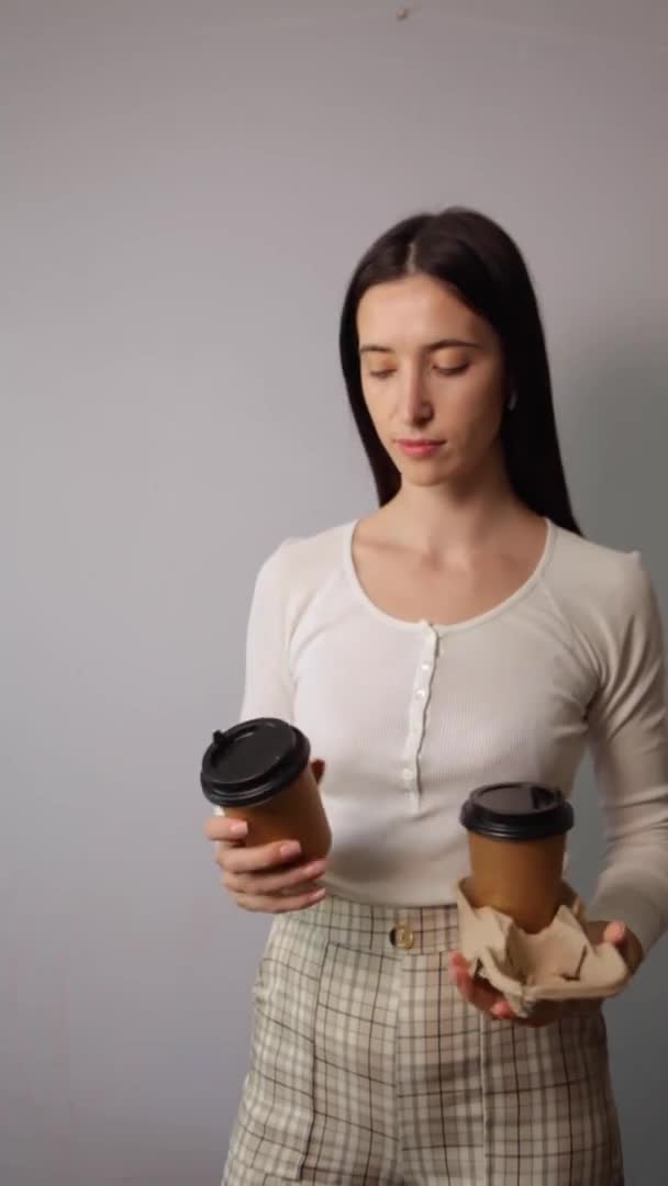 Una mujer sosteniendo dos tazas de papel marrón con tapa negra — Vídeos de Stock