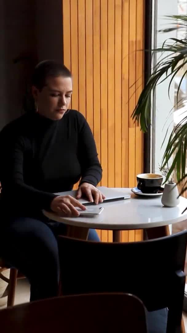 Młoda Dziewczyna Krótkimi Włosami Kolczykiem Nosie Siedzi Kawiarni Pracuje Tablecie — Wideo stockowe