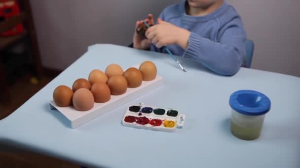 Malé Dítě Maluje Velikonoční Vajíčko Stolu Modrém Pozadí Malý Chlapec — Stock video