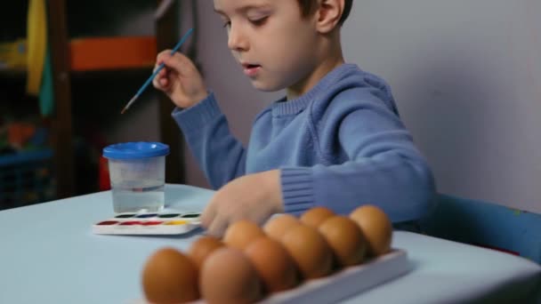 Маленька Дитина Малює Великодні Яйця Столом Синьому Фоні Маленький Хлопчик — стокове відео