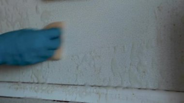 Önlüklü ve lastik eldivenli bir kadın mutfaktaki lavaboda kirli bulaşıkları yıkıyor. Bulaşık yıkamak için lavaboda kirli bulaşıklar.