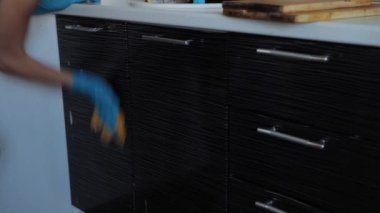 Mutfağı temizliyorum. Eldivenli bir kadın kirli bir yüzeyi siliyor. Güzel bir kadın ev ödevini bez ve sünger kullanarak yapar.