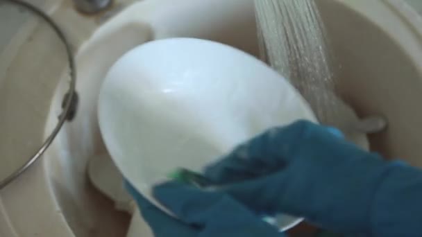 一个穿着围裙和橡胶手套的女人在厨房的水槽里洗脏东西 洗碗槽里的脏盘子 — 图库视频影像