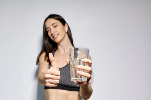 一名身穿运动服 头戴无线耳机的妇女喝水 健康生活方式和体育活动的概念 — 图库照片