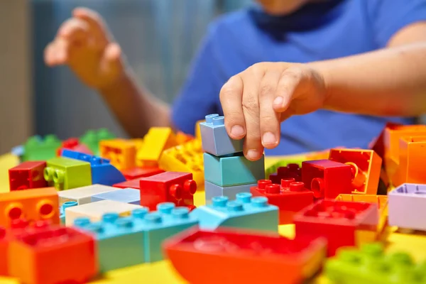 Güzel bir çocuk evde yapı taşlarıyla oynuyor. Şirin, gülümseyen bir çocuk, bir sürü renkli plastik bloğu olan bir lego inşaatçısıyla oynuyor ve bir şehir inşa ediyor. Anaokulu sınıfları.