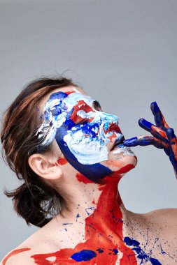 Yüzü boyalı bir kadın portresi. Yaratıcı makyaj ve parlak stil. Yüzü renkli bir kız. Sanat güzelliği. Yüzünde renkli boya olan bir kız.. 