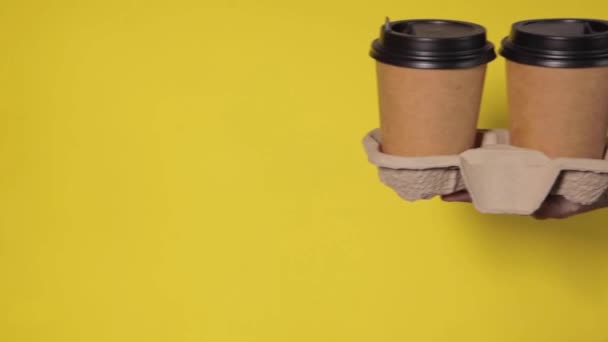 Zbliżenie Żółtym Tle Kobiece Dłonie Trzymają Dwie Papierowe Filiżanki Kawą — Wideo stockowe