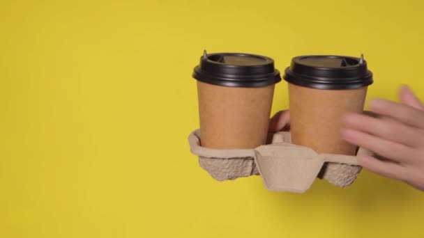 在黄色背景的特写下 女性的手拿着两杯纸杯 咖啡放在摊位上 和你一起喝咖啡或茶 半价促销两杯咖啡 黄色背景的咖啡 — 图库视频影像