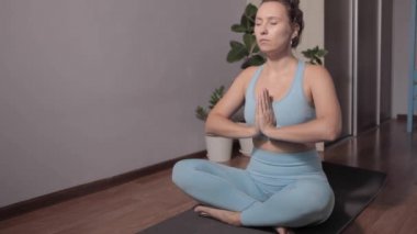 Mavi eşofmanlı genç bir kadın evde antrenman yapıyor, dizüstü bilgisayar kullanıyor, online egzersiz izliyor. Sağlıklı bir yaşam tarzı. Kilo verme ve aşırı kilolardan kurtulma kavramı..