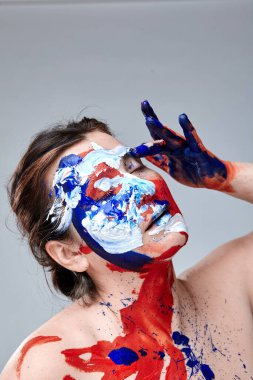 Yüzü boyalı bir kadın portresi. Yaratıcı makyaj ve parlak stil. Yüzü renkli bir kız. Sanat güzelliği. Yüzünde renkli boya olan bir kız.. 