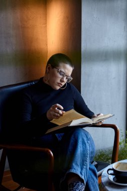 Genç bir kız bir kafede oturmuş kitap okuyor. Eğitim ve uzak çalışma kavramı 