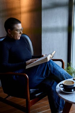 Genç bir kız bir kafede oturmuş kitap okuyor. Eğitim ve uzak çalışma kavramı 