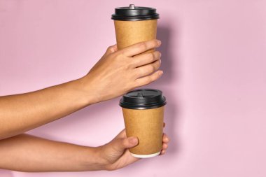 Pembe arka planda yakın plan, bir kadının eli ayakta kahve olan bir kağıt bardağı tutar. Kahve ya da çay. İnsanlar birbirlerine kahve ve kahve dağıtırlar..